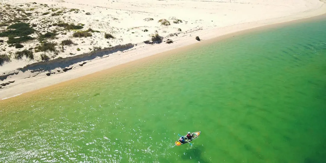 Clear kayak beside a white sand beach