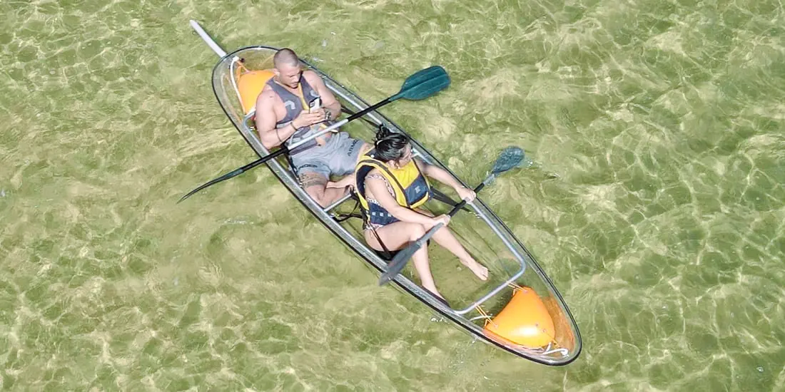 Two guests enjoying a clear kayak over the green lagoon