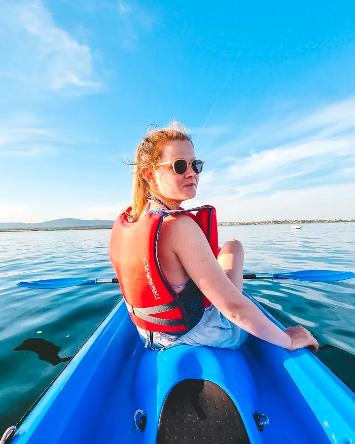 Guest smiling in a blue kayak on calm Ria Formosa water