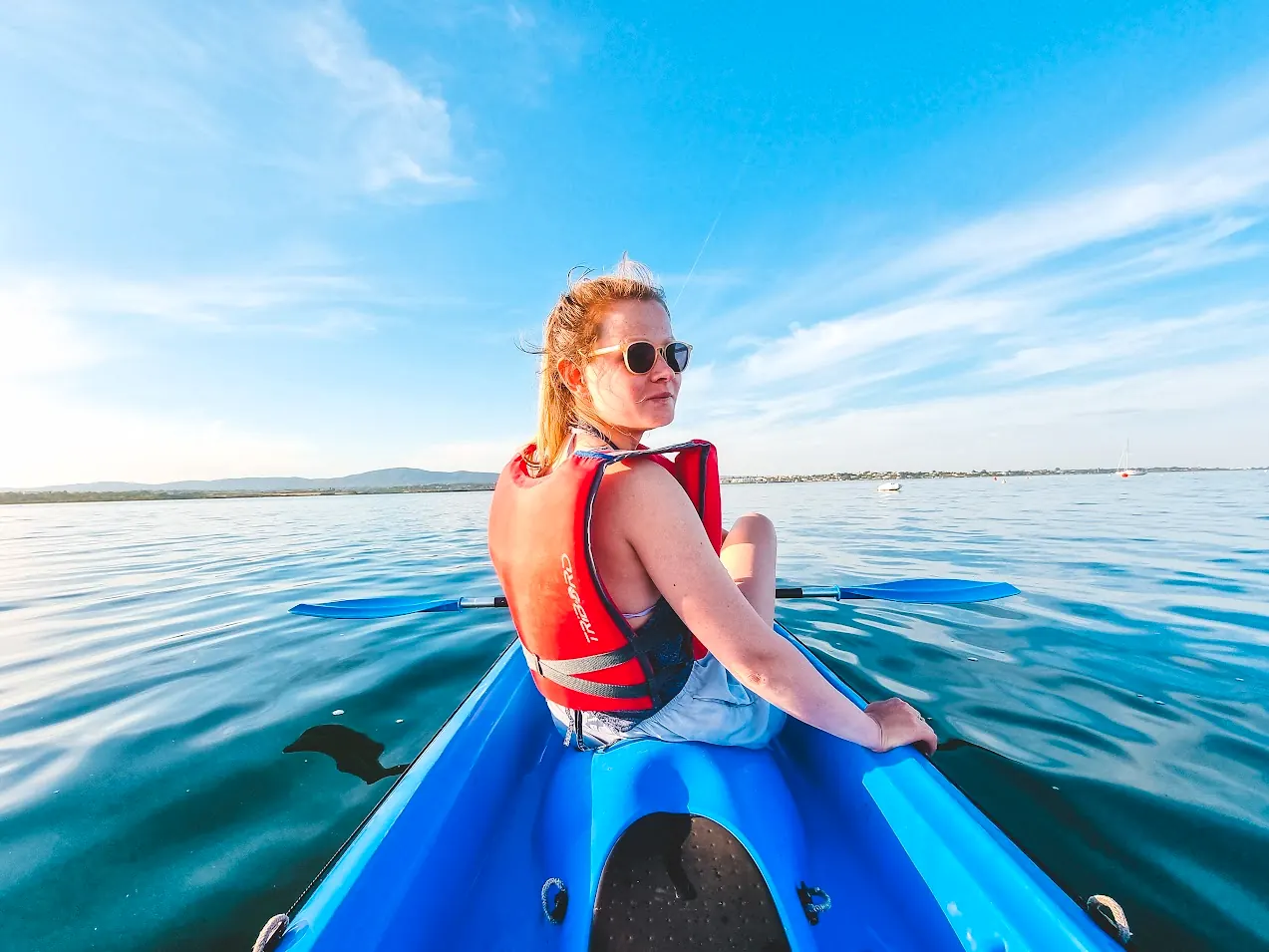 Smiling guest in a blue kayak on calm lagoon water